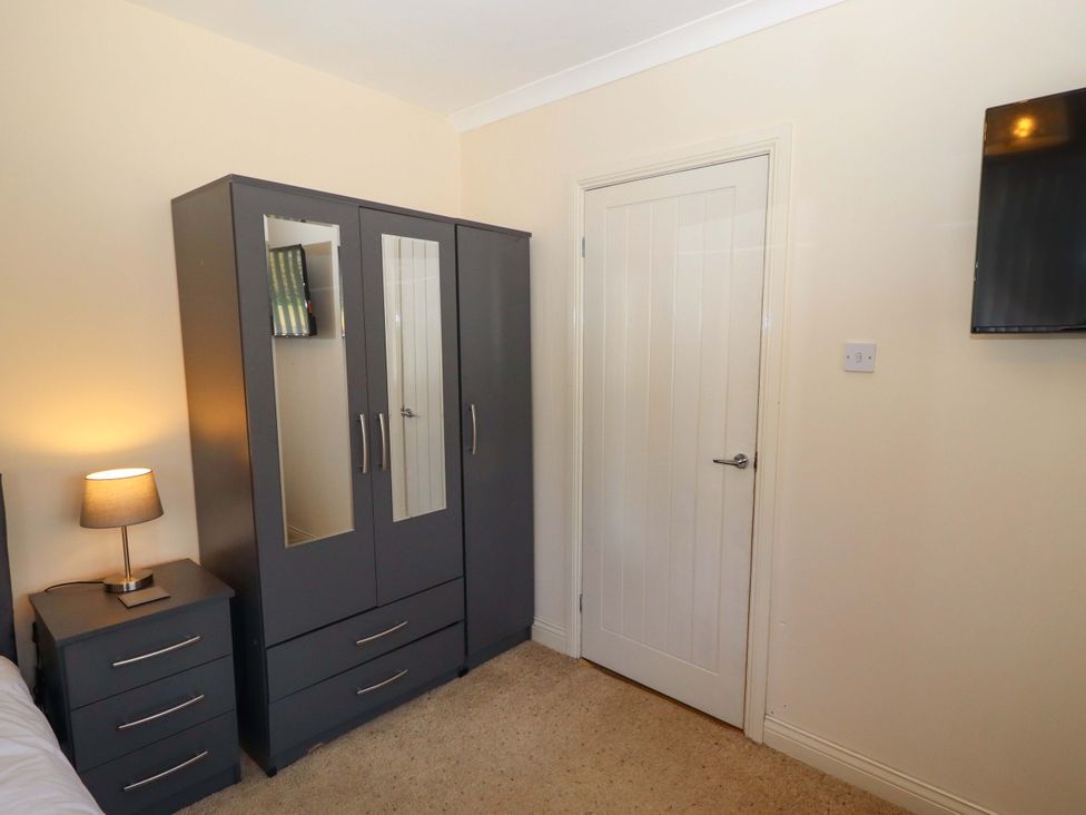 A bedroom with a wardrobe and bedside table at Willow cottage in Seahouses