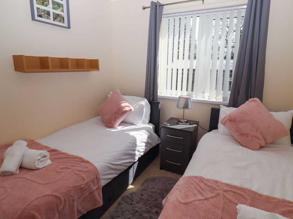 A bedroom with two beds and a nightstand at Willow cottage Seahouses