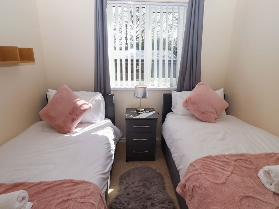 A bedroom with two single beds and a nightstand at Willow cottage in Seahouses