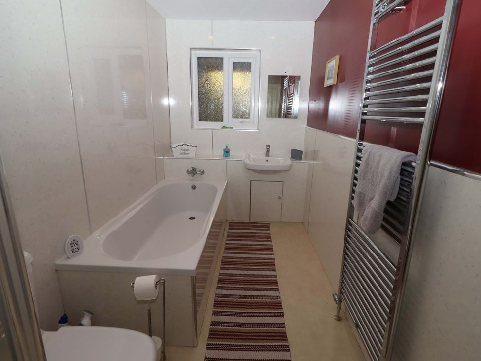 A bathroom with a bath tub and sink at Willow cottage in Seahouses
