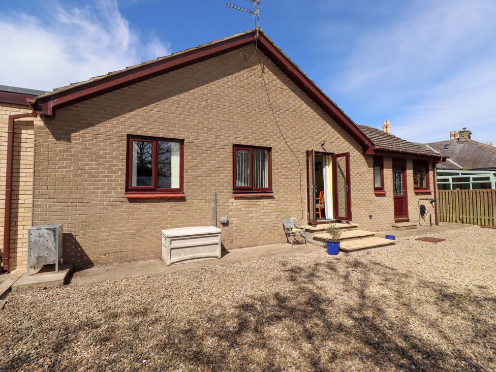 A house with windows and a door leading to a patio area at Willow cottage Seahouses
