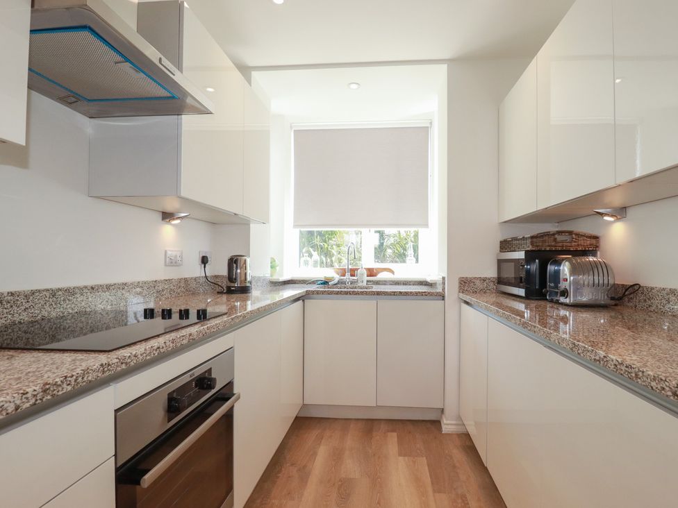 A kitchen with cabinets, a stove, and a sink at Cwtch Treth in Newquay