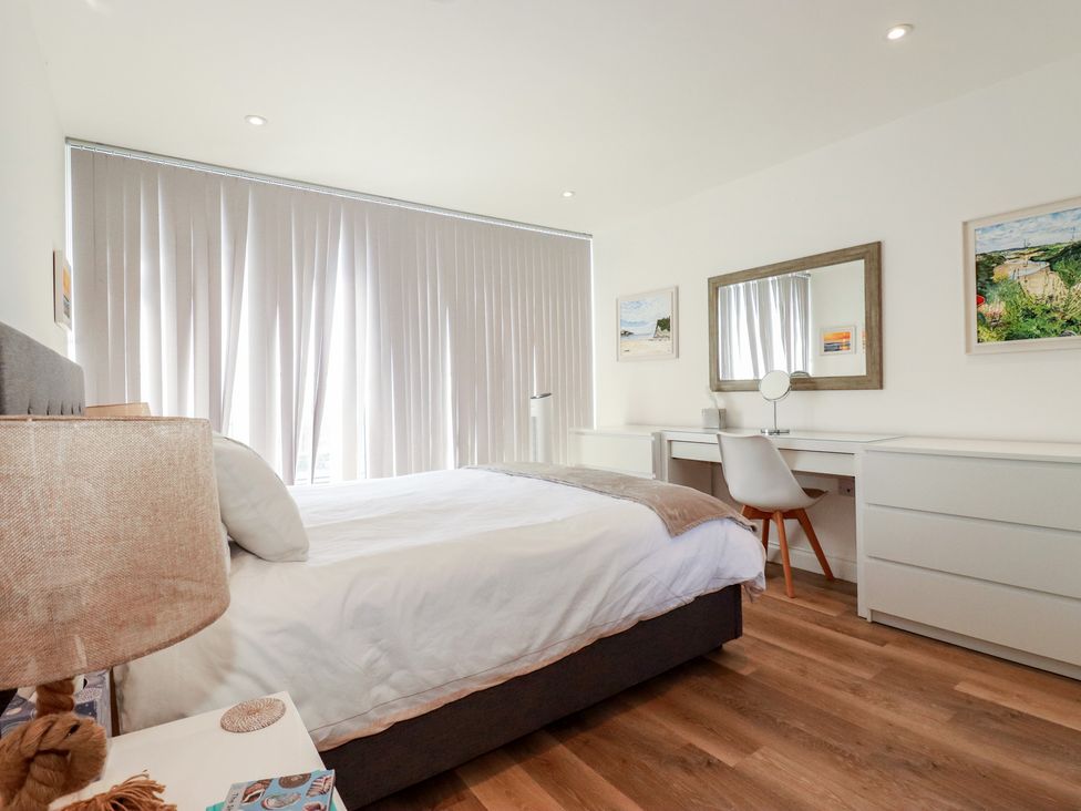 A bedroom with a bed, desk and lamp at Cwtch Treth in Newquay