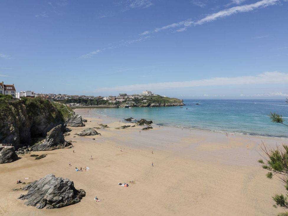 A beach view with cliffs and people at Cwtch Treth in Newquay