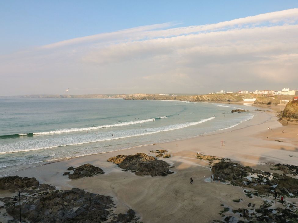 A beach with waves and people at Cwtch Treth in Newquay