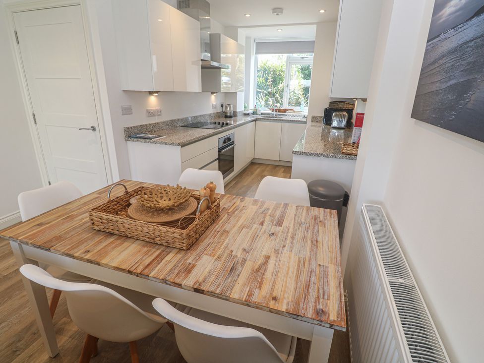 A kitchen with a dining table and chairs at Cwtch Treth in Newquay