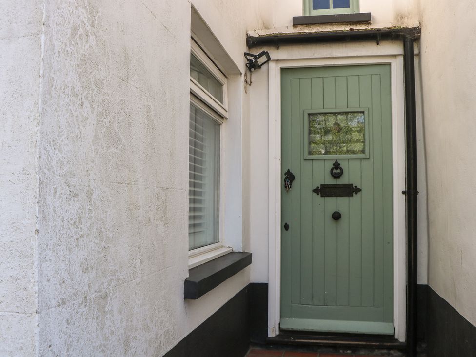 An entrance with a green door and a window at Smugglers Cottage in Selsey