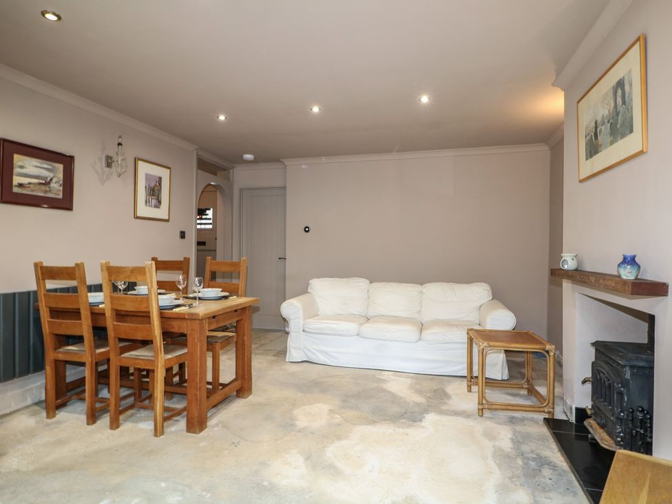 A living room with a dining area and fireplace at Smugglers Cottage in Selsey