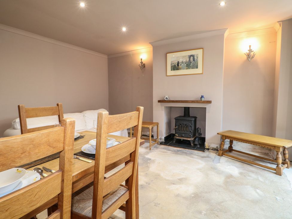A living room with a dining table and fireplace at Smugglers Cottage in Selsey