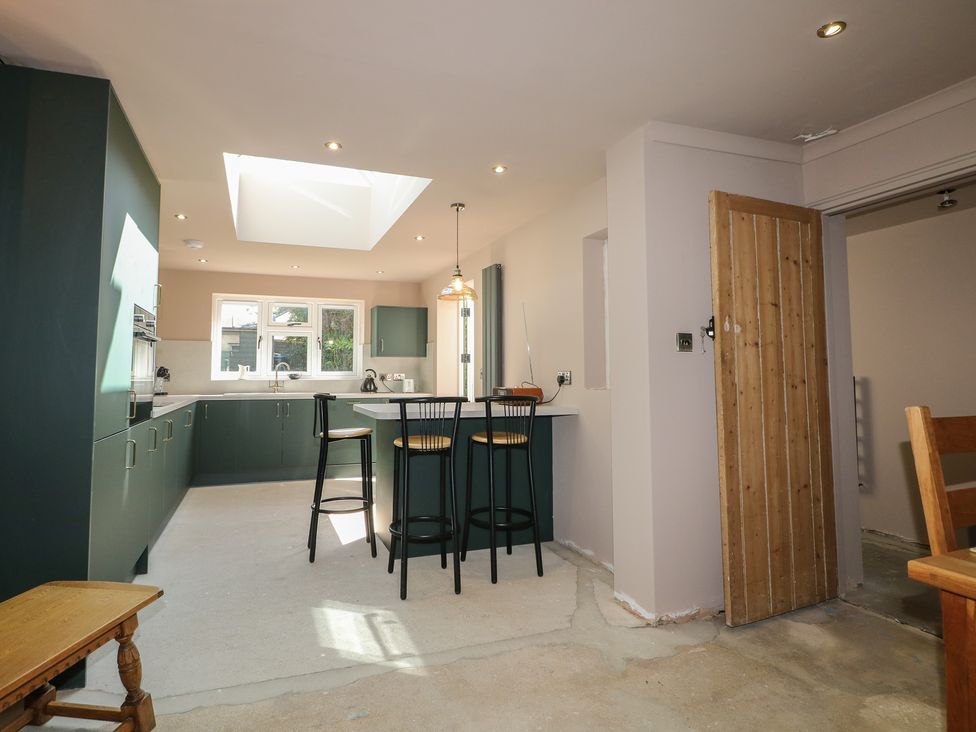 A kitchen with bar stools and skylight at Smugglers Cottage in Selsey