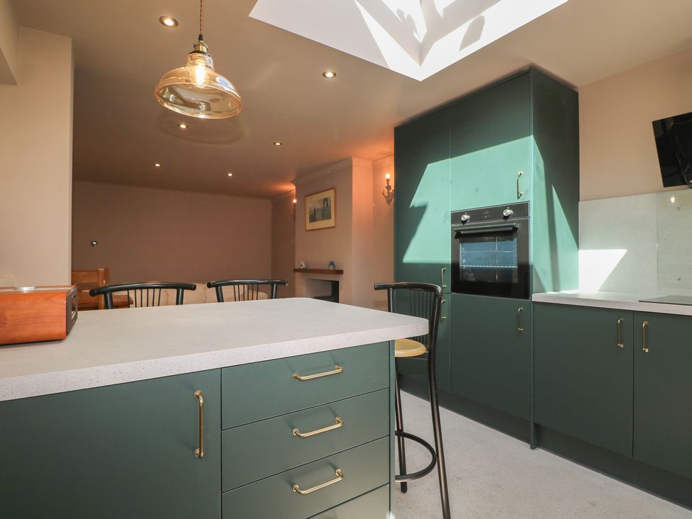 A kitchen with a kitchen island and stools at Smugglers Cottage in Selsey