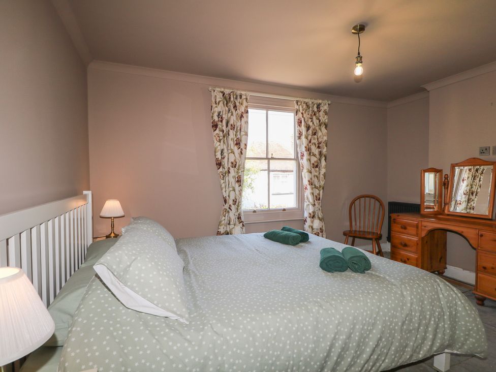 A bedroom with a bed and dressing table at Smugglers Cottage in Selsey