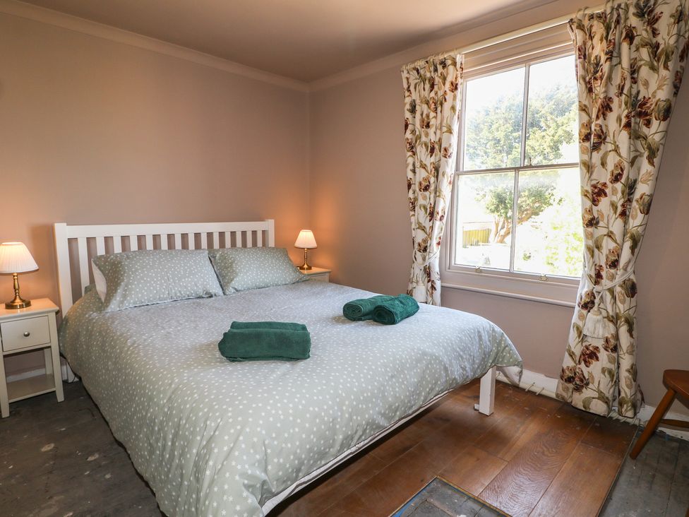 A bedroom with a bed and nightstand at Smugglers Cottage in Selsey