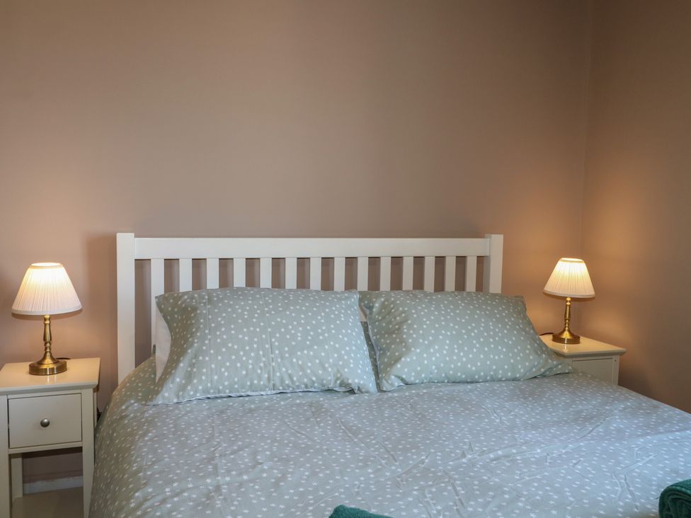 A bedroom with a bed and bedside tables at Smugglers Cottage in Selsey