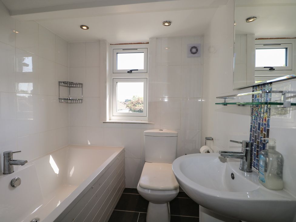 A bathroom with a bathtub, toilet, and sink at Smugglers Cottage in Selsey