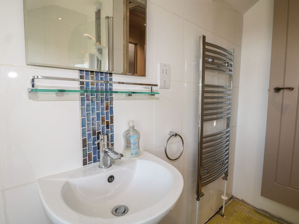 A bathroom with a sink and towel rail at Smugglers Cottage in Selsey