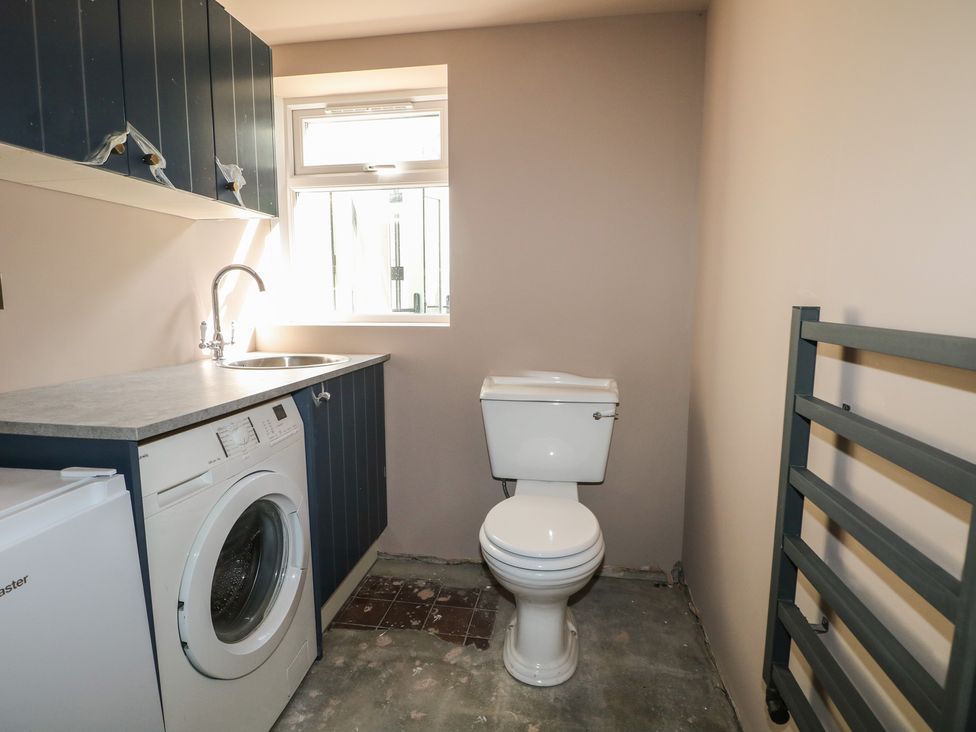 A laundry room with a washing machine and sink at Smugglers Cottage in Selsey