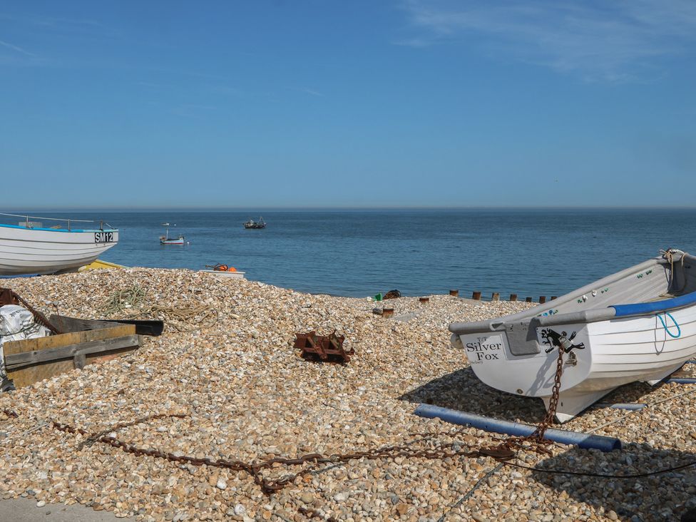 Boats on a pebbled shore by the ocean at Smugglers Cottage in Selsey
