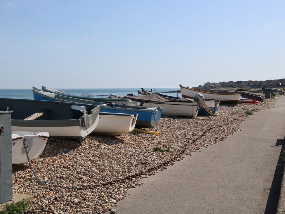 Boats on pebbles next to water at Smugglers Cottage Selsey