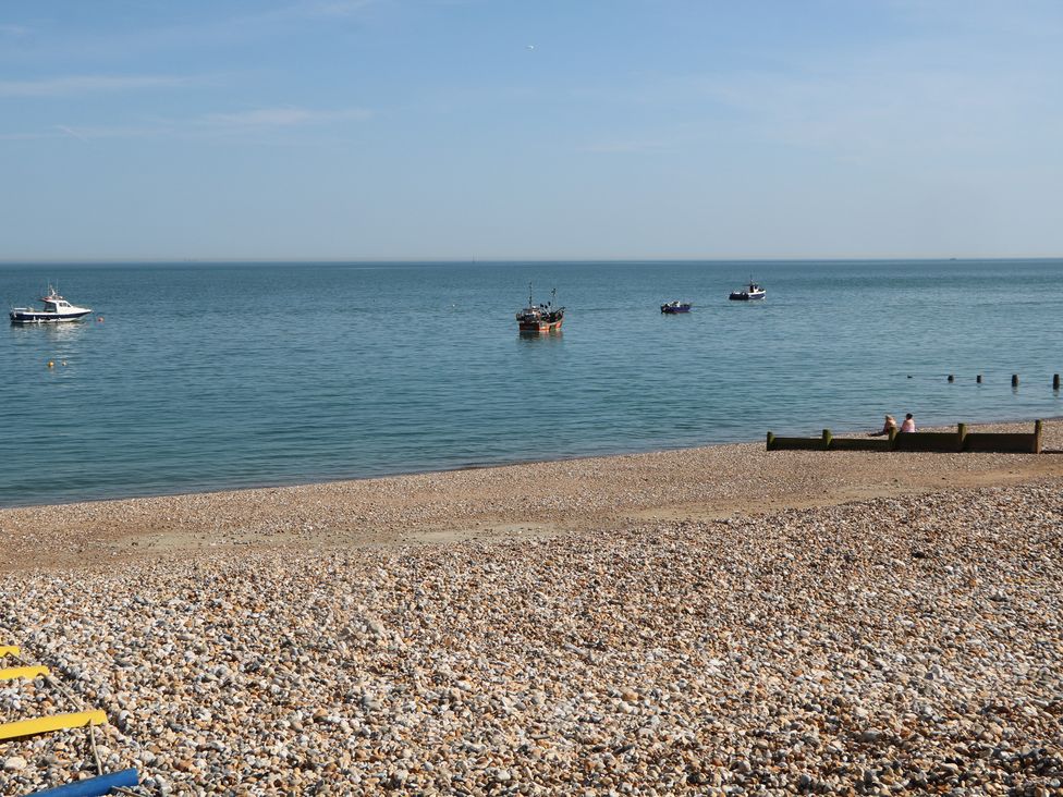 A beach with boats on water at Smugglers Cottage in Selsey