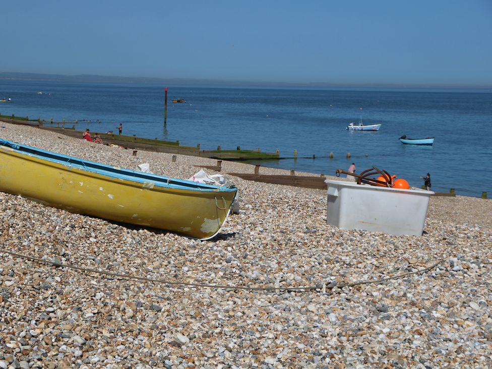 A yellow boat and a white container on a beach at Smugglers Cottage Selsey