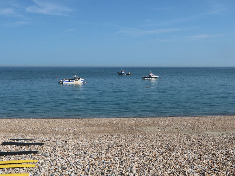 A beach with boats in the water at Smugglers Cottage in Selsey