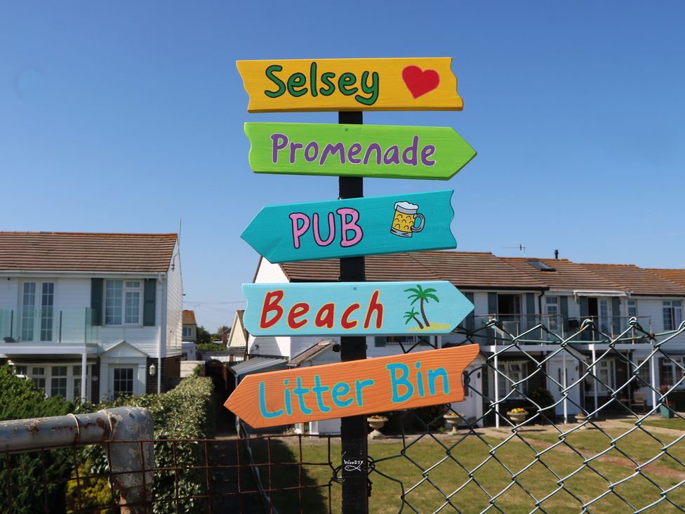 A signpost pointing to Selsey Promenade, Pub, Beach, and Litter Bin at Smugglers Cottage in Selsey