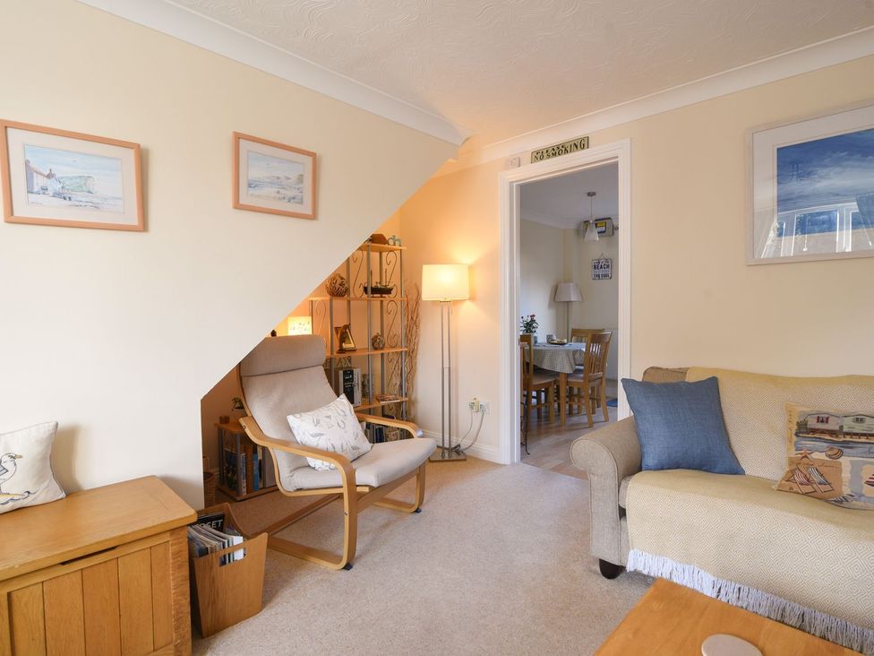 A living room with an armchair and bookshelf at Mead Cottage in Bridport