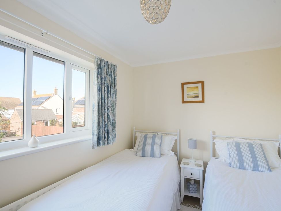 A bedroom with two beds and a window at Mead Cottage in Bridport