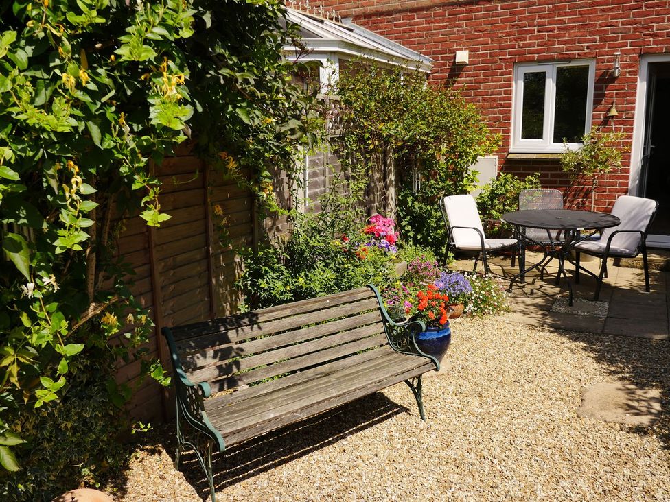A garden with a bench, table, and chairs at Mead Cottage in Bridport