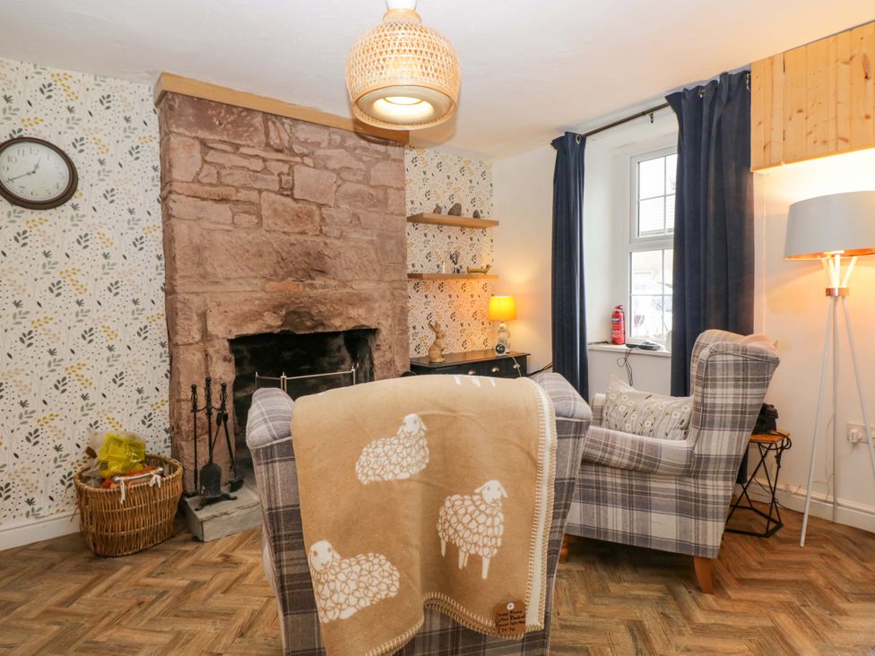 A living room with a fireplace and armchair at The Old Post Office in Whitehaven