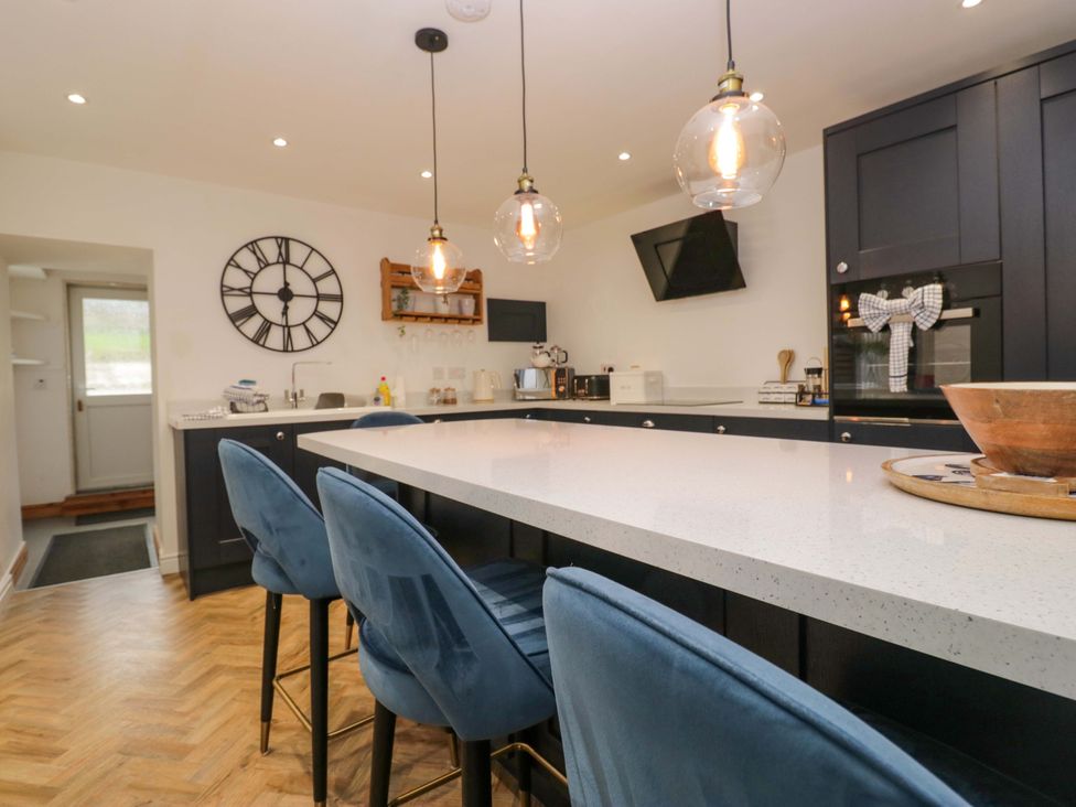 A kitchen with a central island and bar stools at The Old Post Office in Whitehaven