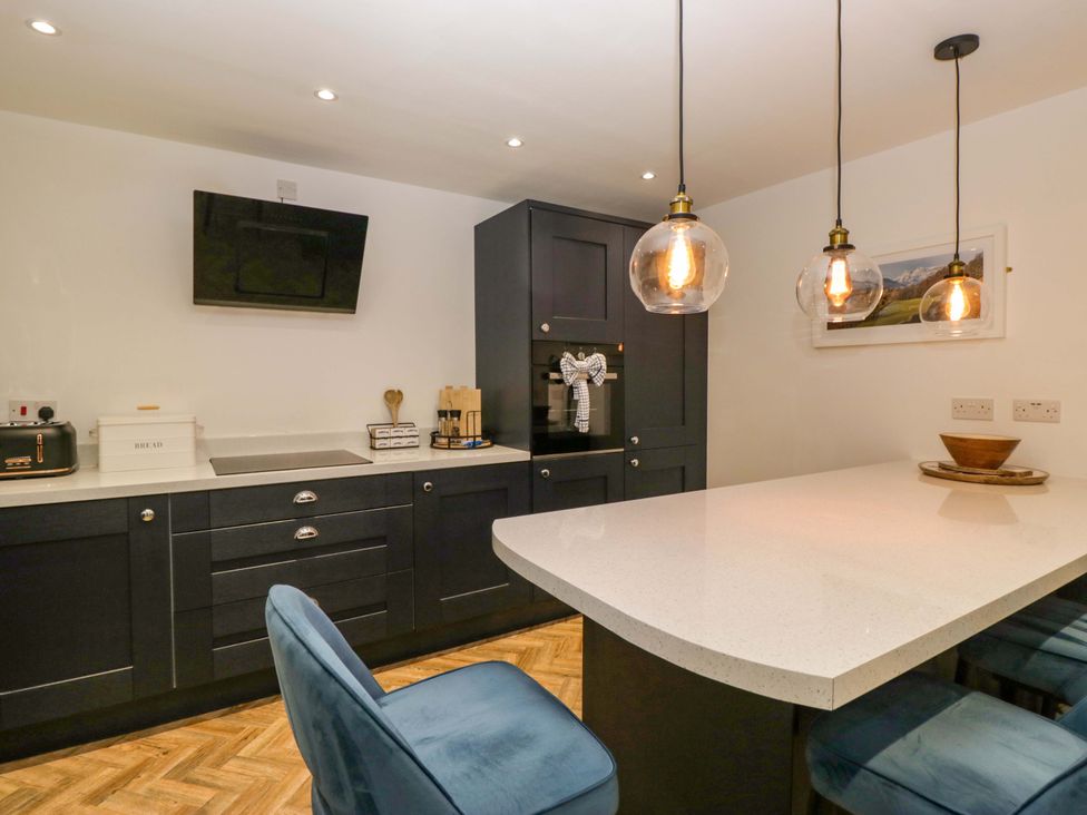 A kitchen with an island and bar stools at The Old Post Office in Whitehaven