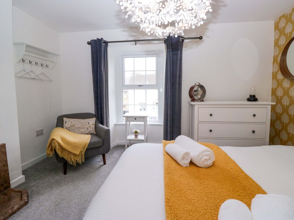 A bedroom with a bed, chair, and window at The Old Post Office in Whitehaven