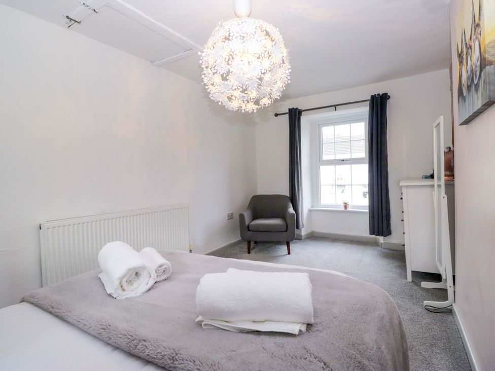 A bedroom with a bed, chair, and window at The Old Post Office in Whitehaven