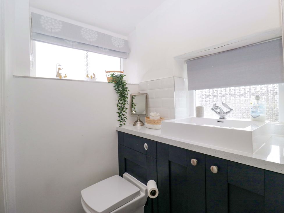 A bathroom featuring a toilet and sink with a cabinet at The Old Post Office in Whitehaven