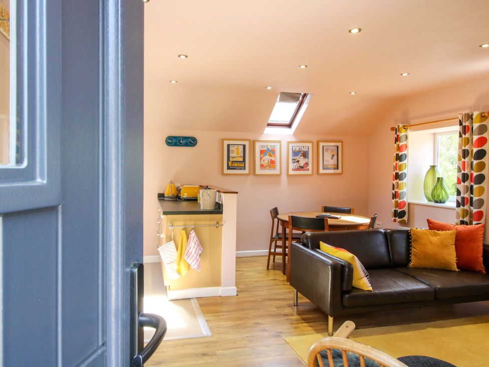 A living room with a kitchen unit and dining table at Pentwyn Barn in Clyro