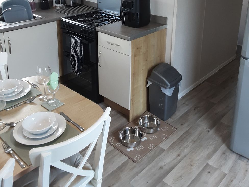 A kitchen with a dining table set and pet food bowls at Josephine MB37 in Newquay