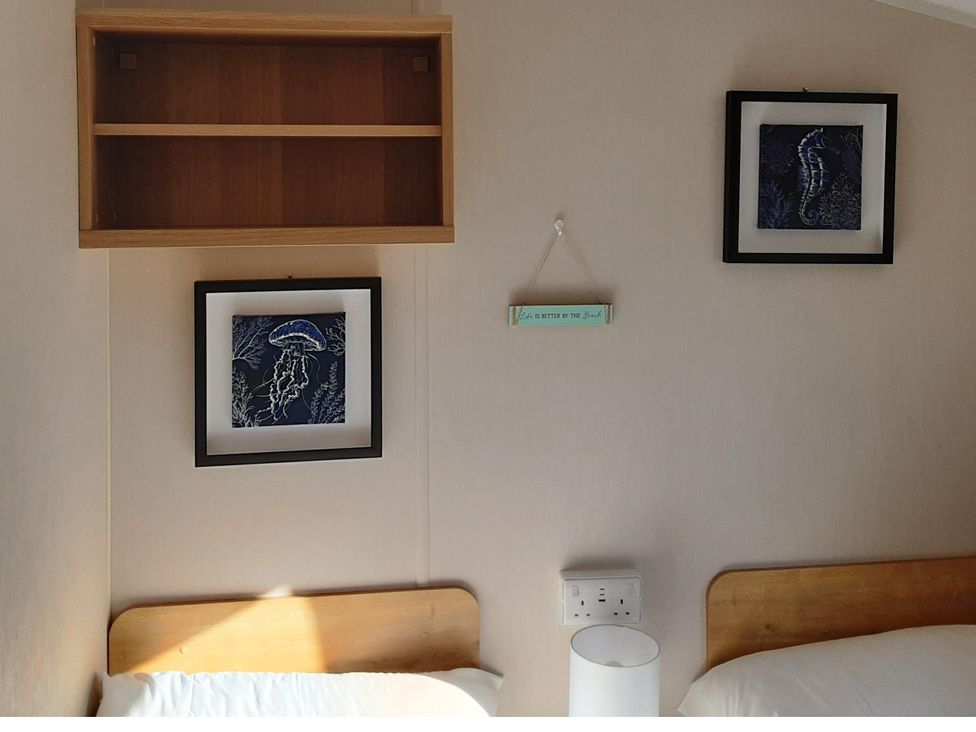 A bedroom with two beds and wall decorations at Josephine MB37, Newquay