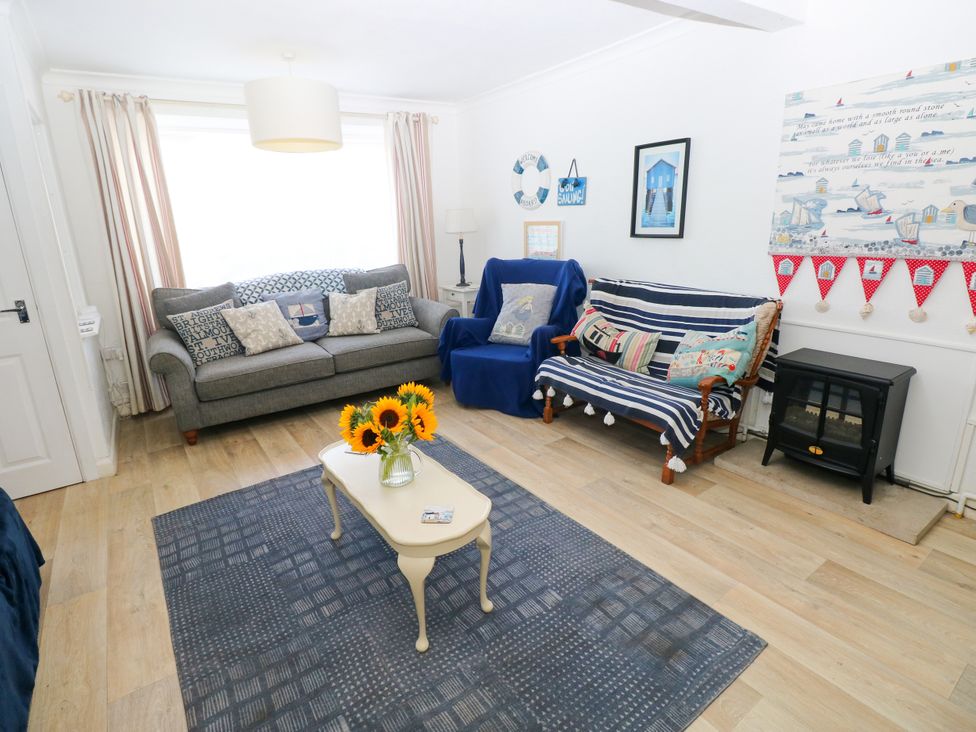 A living room with a sofa, chair, coffee table, and wall art at 3 Edward Street in Tenby