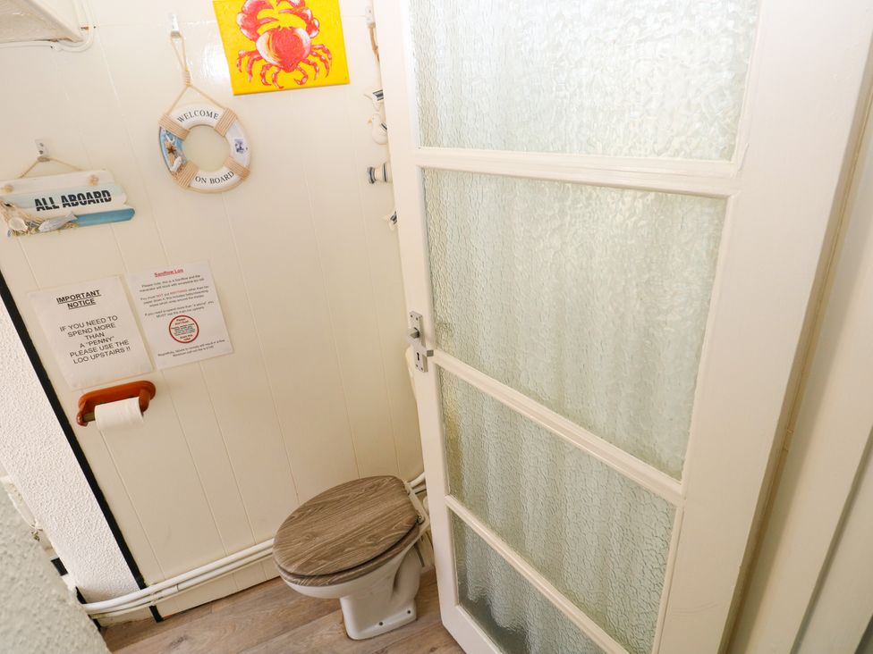 A bathroom with a toilet and wall decorations at 3 Edward Street in Tenby