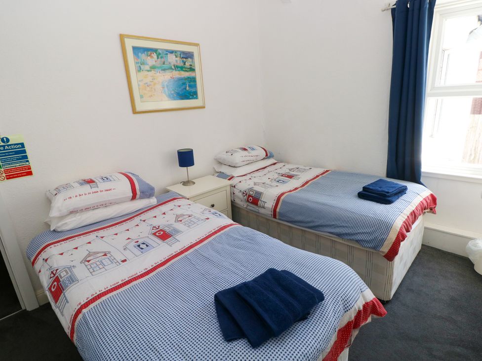 A bedroom with two single beds and a bedside lamp at 3 Edward Street in Tenby