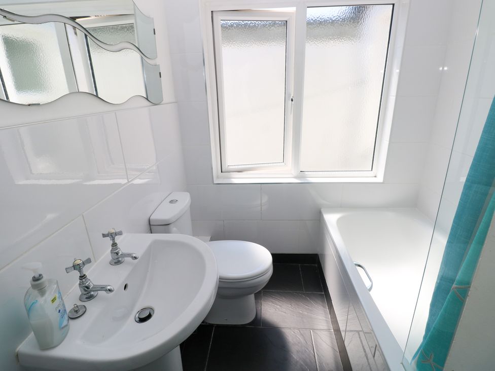 A bathroom with a sink, toilet, bathtub, and window at 3 Edward Street, Tenby