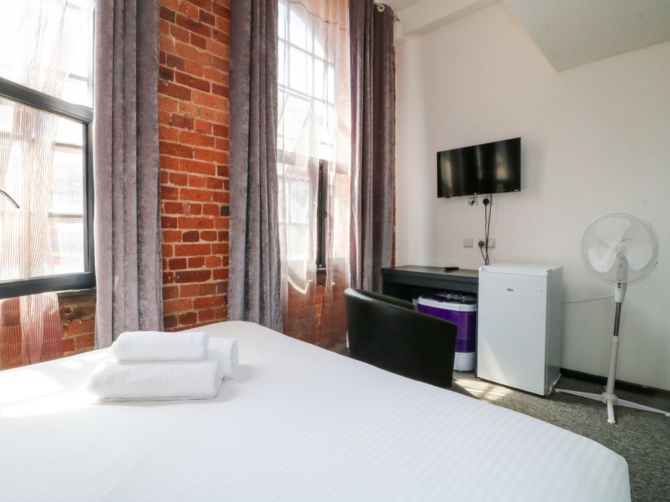 A bedroom with a bed and windows with curtains at Apartment 310 in Nottingham