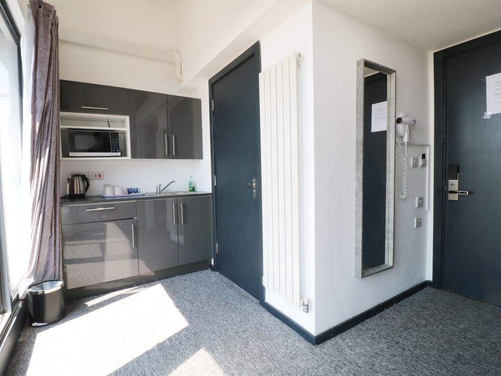A kitchen area with a microwave, sink, kettle, and cupboard at Apartment 610 Nottingham