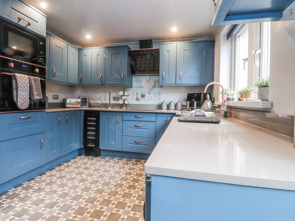 A kitchen with blue cabinets and appliances at 2 Rock View Settle