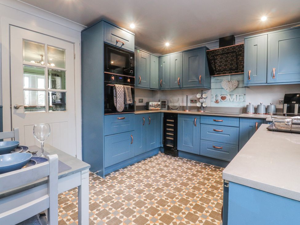 A kitchen with blue cabinets and appliances at 2 Rock View Settle