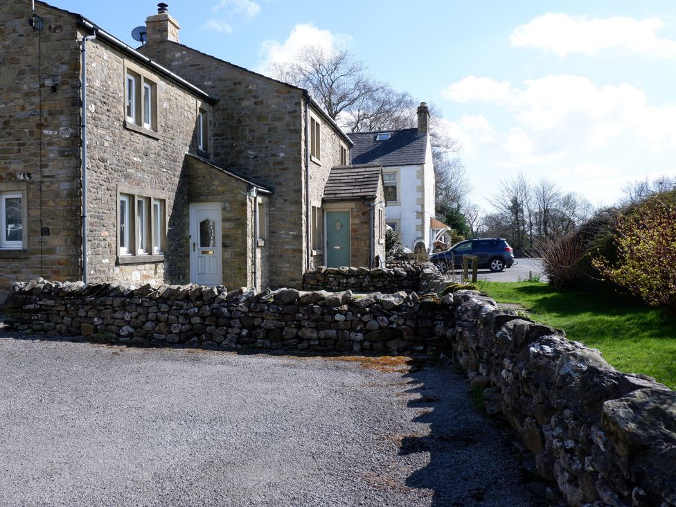 A stone house with a gravel driveway and a car at 2 Rock View near Settle