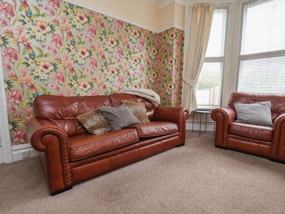 A living room with brown leather sofa and armchair at 30 Prospect Hill in Whitby