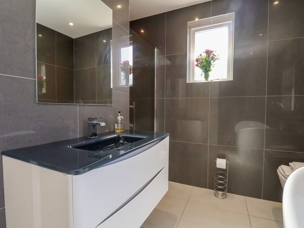 A bathroom with a sink, mirror, shower, and toilet at 30 Prospect Hill in Whitby